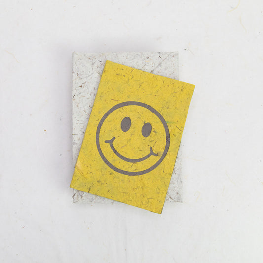 eco-friendly paper greeting card in yellow with smiley face on top of eco-friendly envelope in natural color